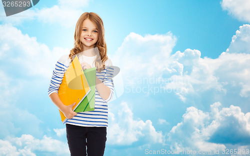 Image of happy girl holding colorful folders over blue sky