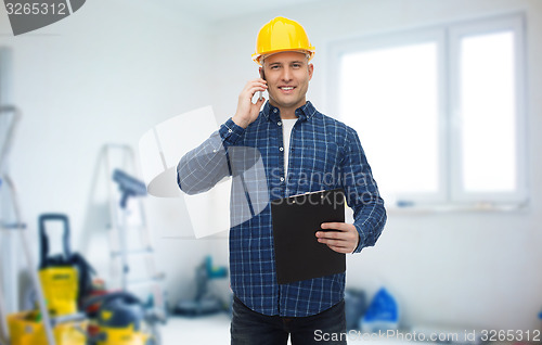 Image of smiling builder in helmet calling on smartphone