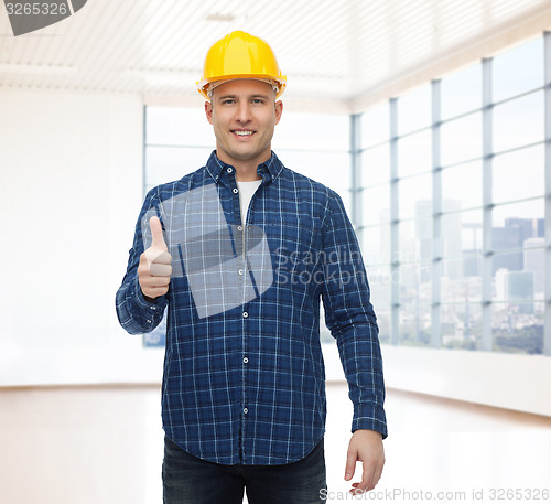 Image of smiling male builder in helmet showing thumbs up