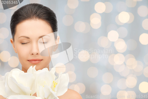 Image of beautiful woman smelling flowers with closed eyes