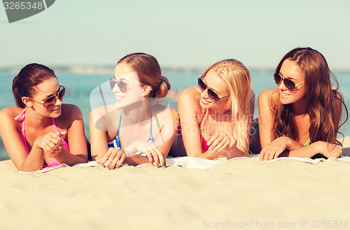 Image of group of smiling women in sunglasses on beach