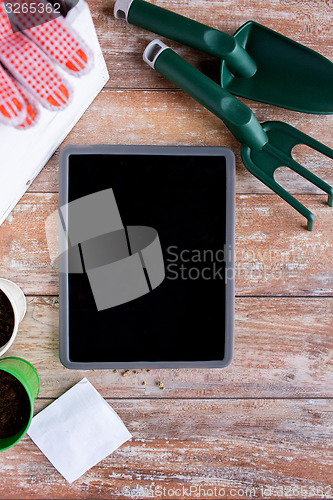 Image of close up of tablet pc and garden tools on table