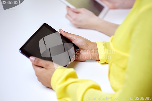 Image of close up of female hands with tablet pc at table