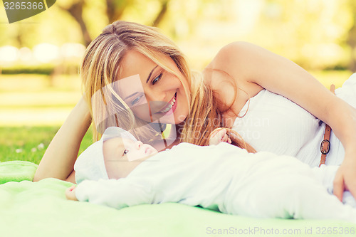 Image of happy mother lying with little baby on blanket