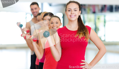 Image of group of smiling people with dumbbells in the gym