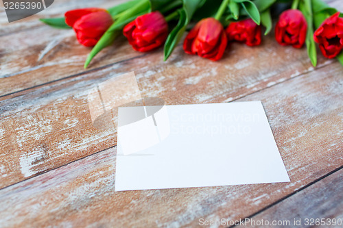 Image of close up of red tulips and blank paper or letter