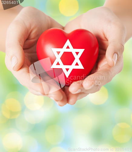 Image of close up of hands holding heart with jewish star