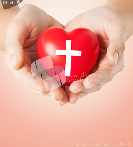 Image of close up of hands holding heart with cross symbol