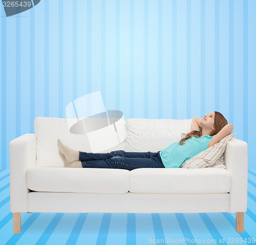 Image of smiling little girl lying on sofa and dreaming