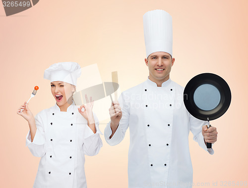 Image of happy chefs or cooks couple with kitchenware