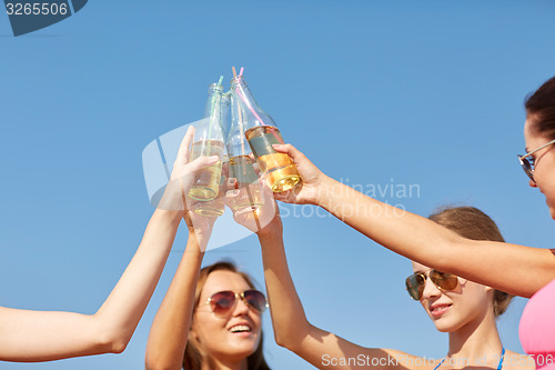 Image of close up of happy young women clinking bottles