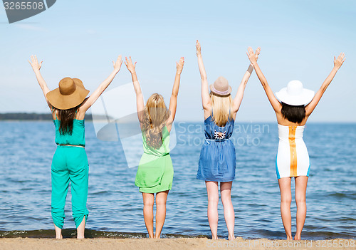 Image of girls looking at the sea with hands up