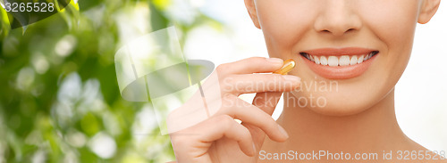 Image of beautiful woman holding omega 3 vitamins capsule