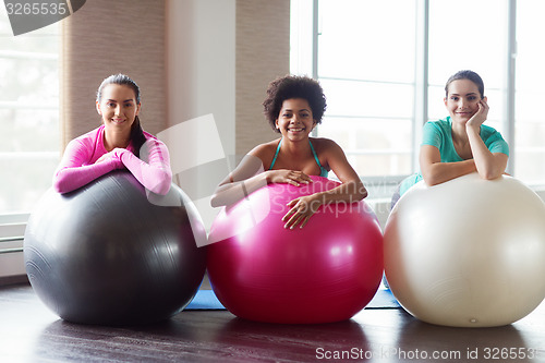 Image of group of smiling women with exercise balls in gym