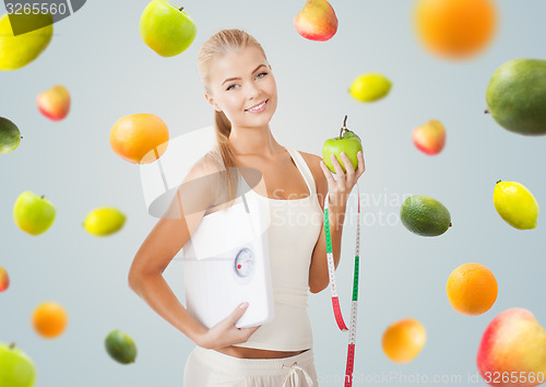 Image of sporty woman with scale, apple and measuring tape