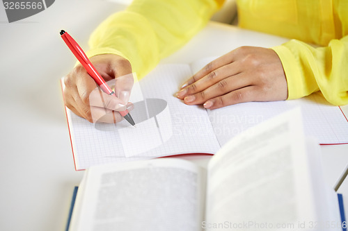 Image of close up of female hands writing to notebook
