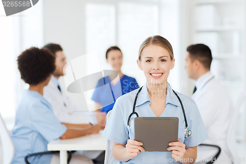 Image of happy doctor with tablet pc over team at clinic