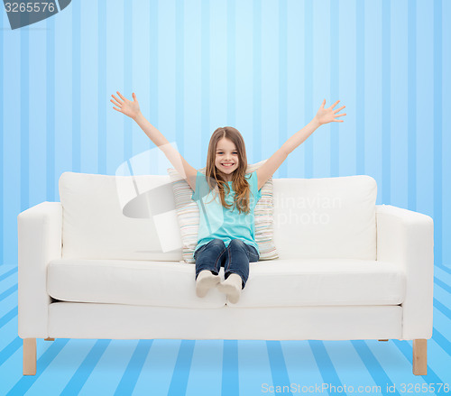 Image of happy girl sitting on sofa with raised hands