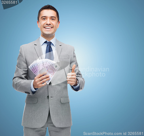 Image of smiling businessman with money showing thumbs up