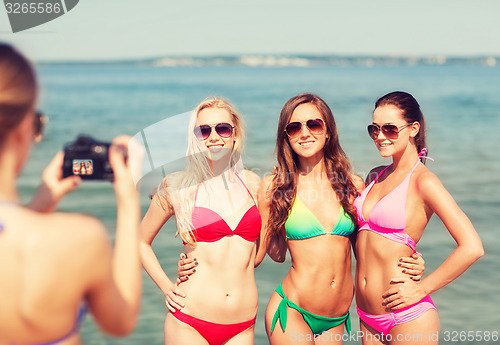 Image of group of smiling women photographing on beach