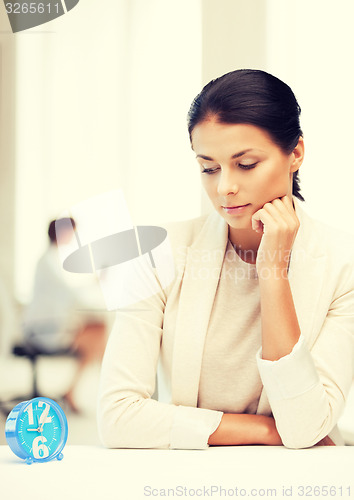 Image of businesswoman looking at alarm clock