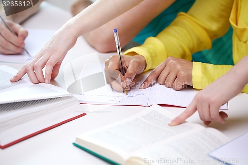 Image of close up of students hands writing to notebooks