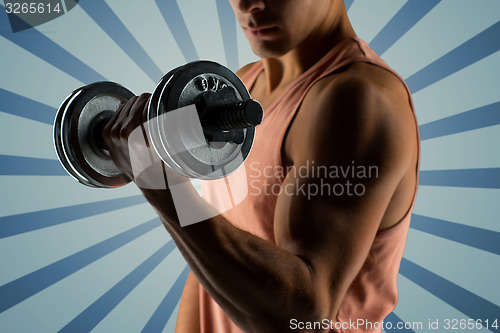 Image of close up of young man with dumbbell flexing biceps