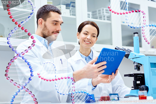 Image of scientists with tablet pc and microscope in lab