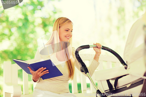 Image of happy mother with book and stroller in park