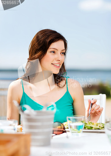 Image of girl eating in cafe on the beach