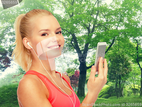 Image of smiling sporty woman with smartphone and earphones