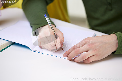 Image of close up of male hands writing to notebook