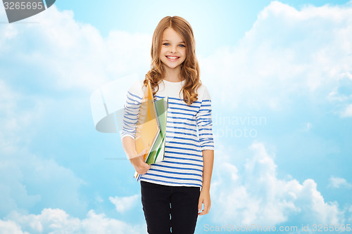 Image of happy girl holding colorful folders over blue sky