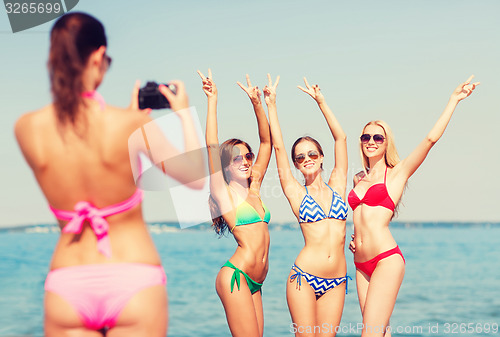 Image of group of smiling women photographing on beach