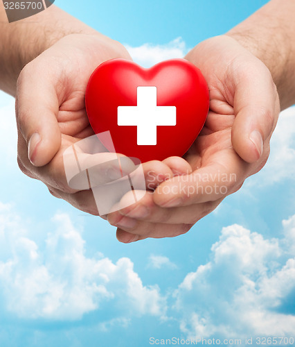 Image of male hands holding red heart with white cross