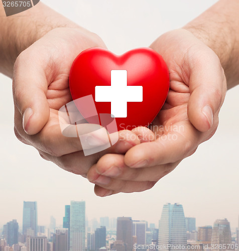 Image of male hands holding red heart with white cross