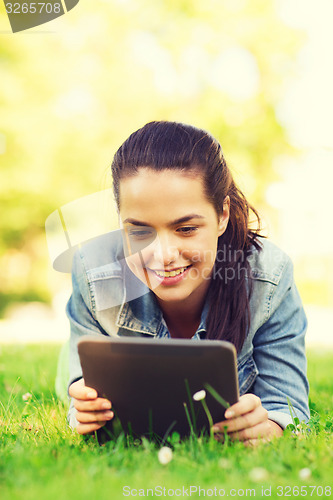 Image of smiling young girl tablet pc lying on grass
