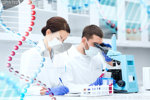 Image of scientists with clipboard and microscope in lab