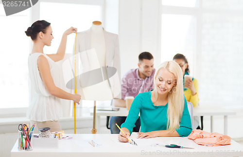 Image of smiling fashion designers working in office