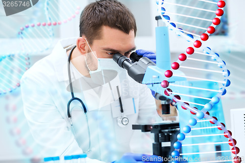 Image of young scientist looking to microscope in lab