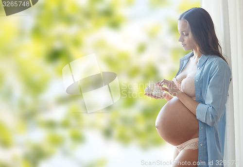 Image of happy pregnant woman with baby booties at home