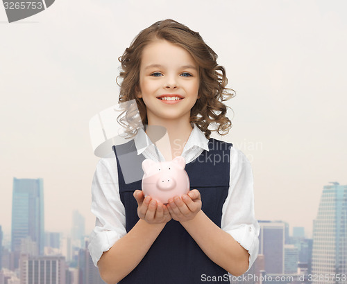 Image of happy girl holding piggy bank on palms