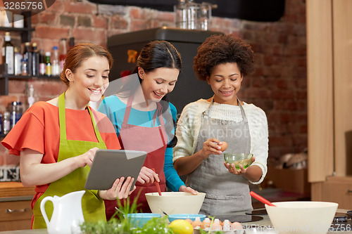 Image of happy women with tablet pc cooking in kitchen