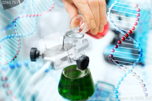 Image of close up of scientist filling test tubes in lab