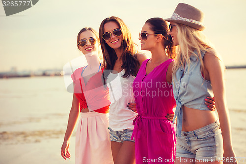 Image of group of smiling women in sunglasses on beach