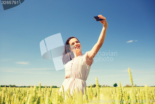 Image of smiling girl with smartphone on cereal field