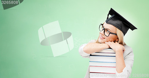 Image of happy student in mortar board cap with books