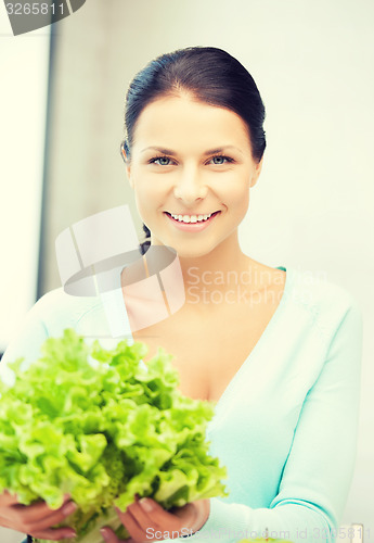 Image of woman in the kitchen with green salad leaves