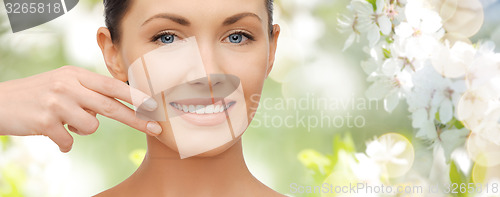 Image of face and hand of smiling woman over summer garden