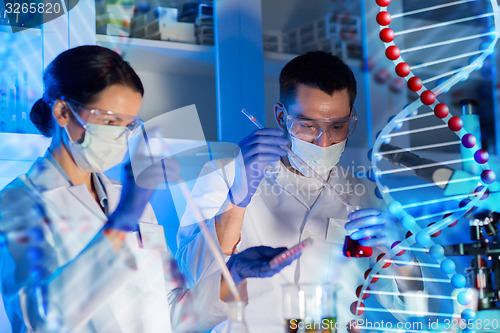 Image of scientists with pipettes and test tubes in lab